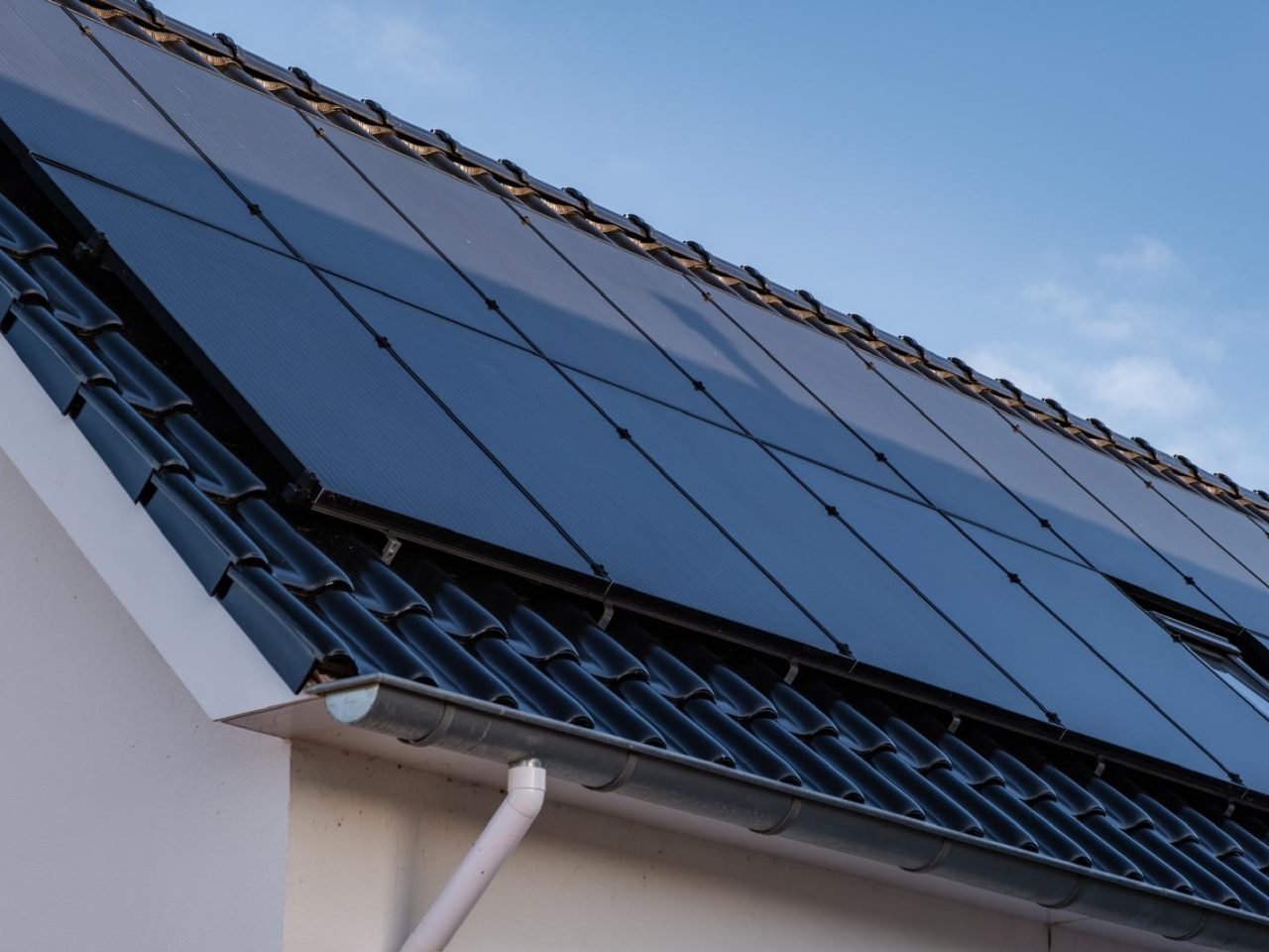 Zonnepanelen op een schuin pannendak in de zon, - Jazz Electro voor duurzame energieopwekking.
